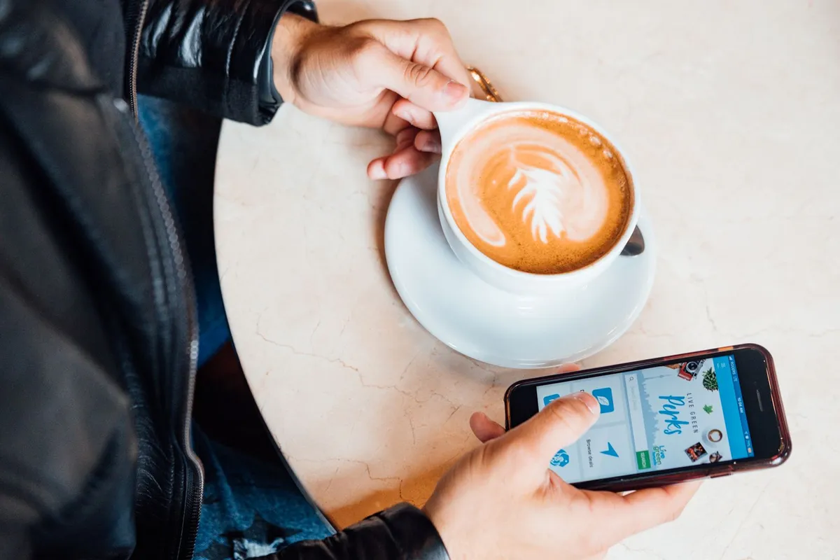 τι είναι το QR menu: πελάτης σε καφέ διαβάζει το ψηφιακό μενού στο κινητό δίπλα σε έναν καφέ